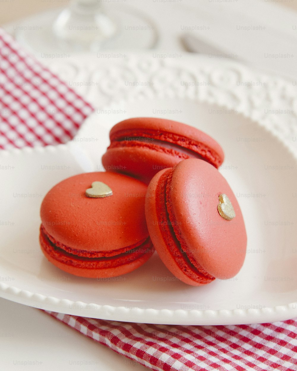 a white plate topped with red macaroons on top of a table