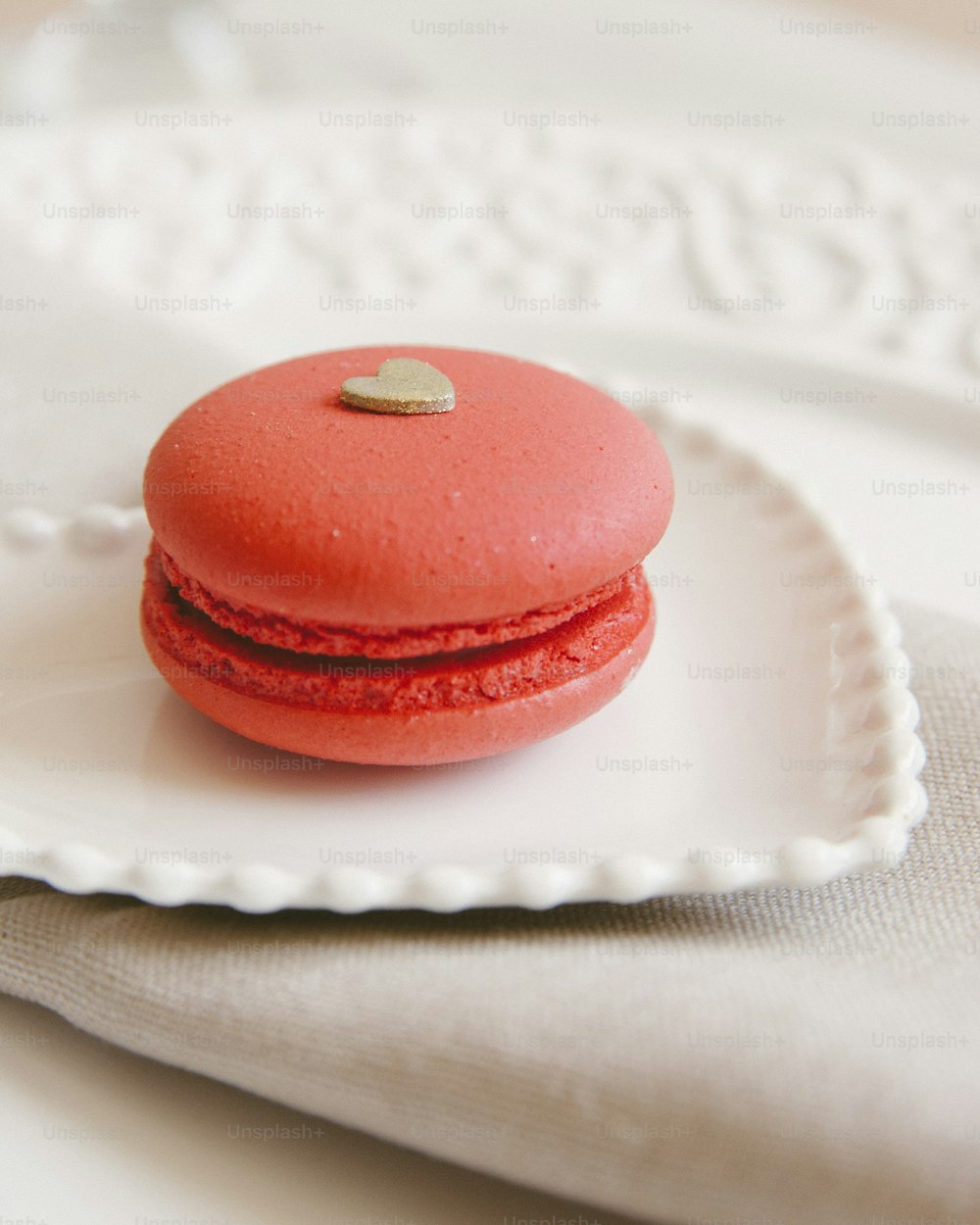 a red macaroon sitting on a white plate