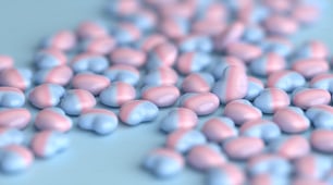 um monte de pílulas rosa e azul em uma superfície azul