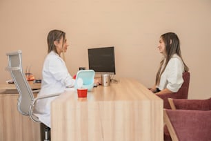 two women sitting at a desk talking to each other
