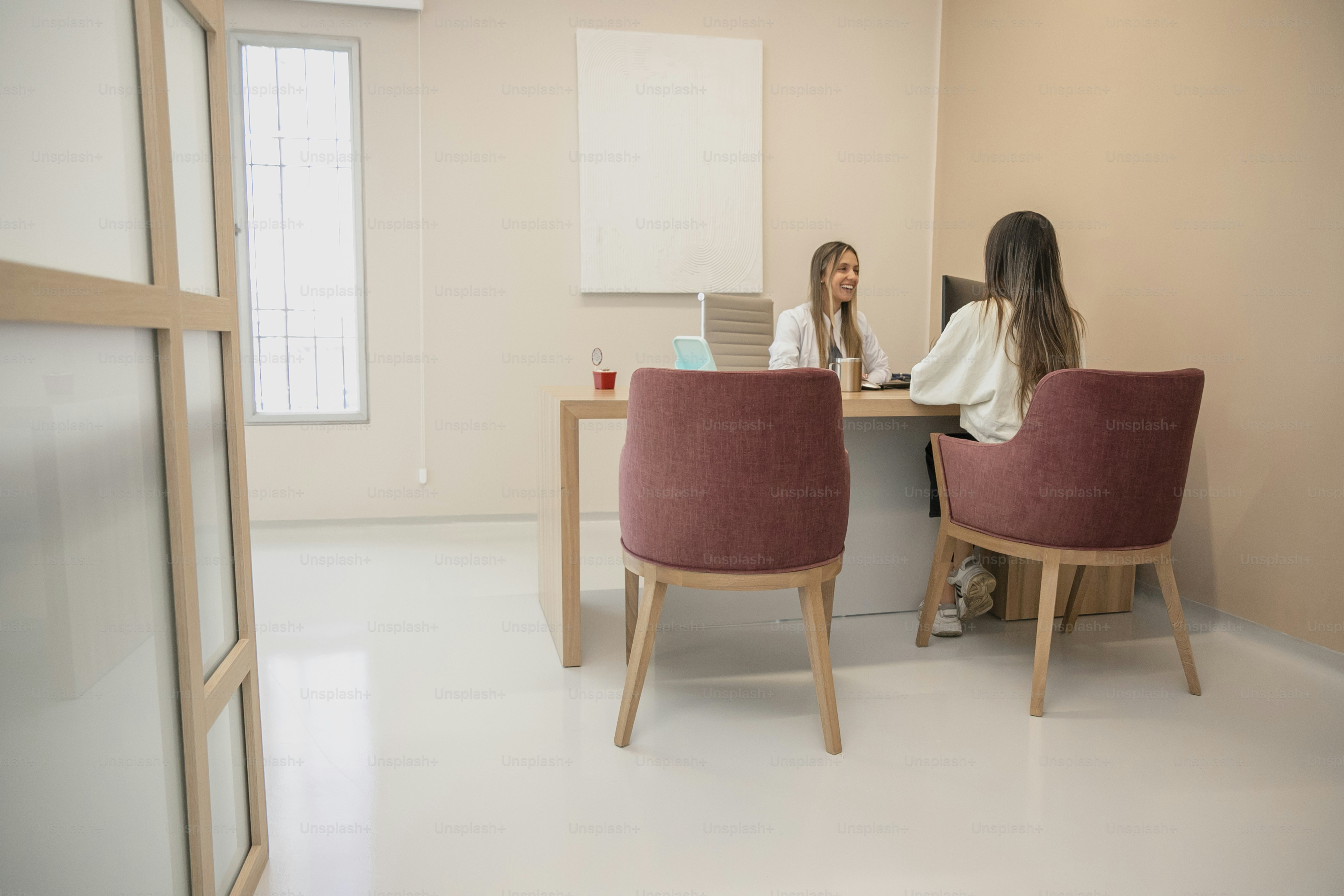 two women sitting at a desk with a laptop