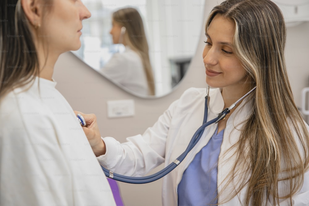a woman in a white lab coat is listening to a woman in a white coat