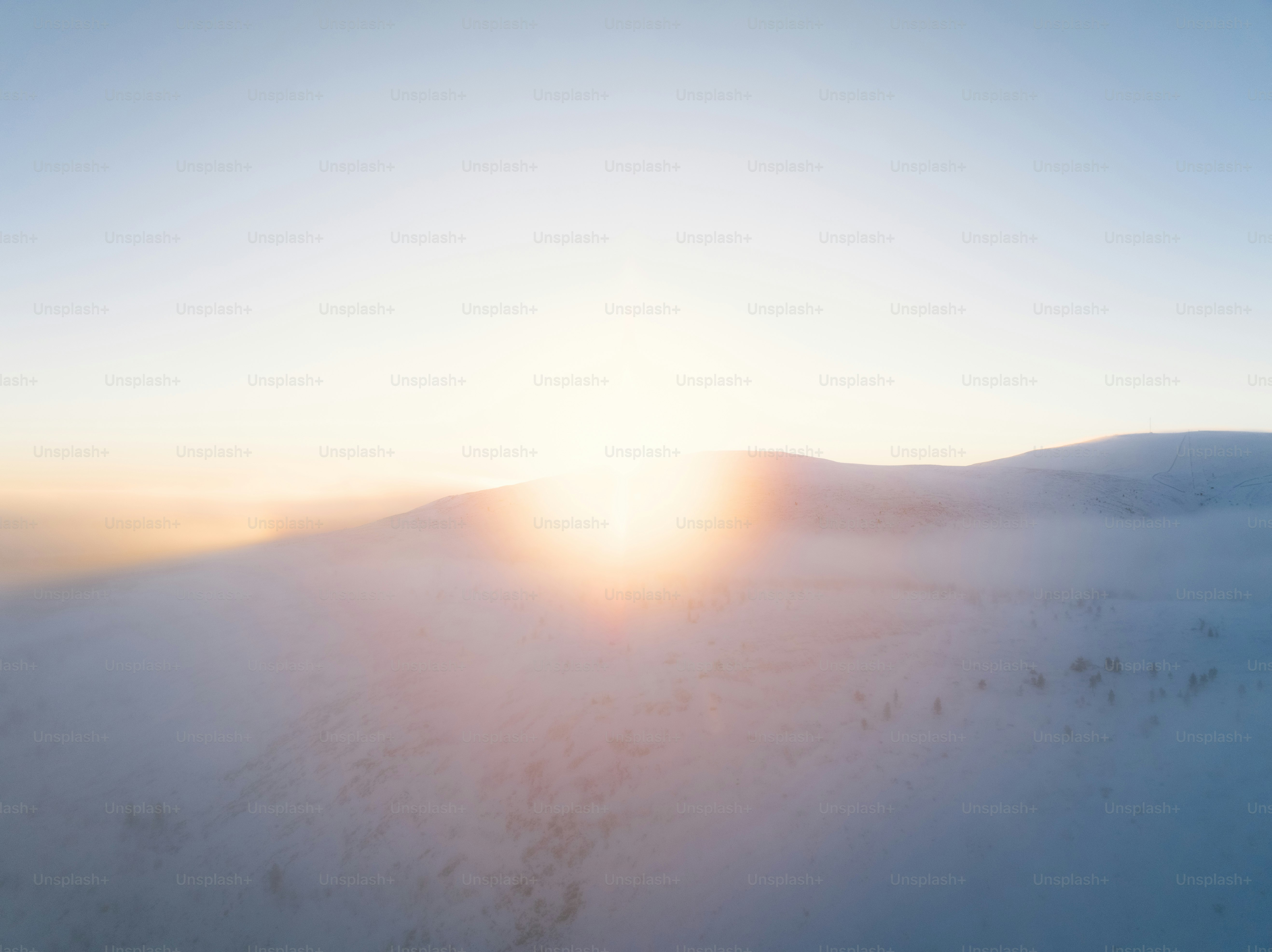 the sun is setting over a snowy mountain