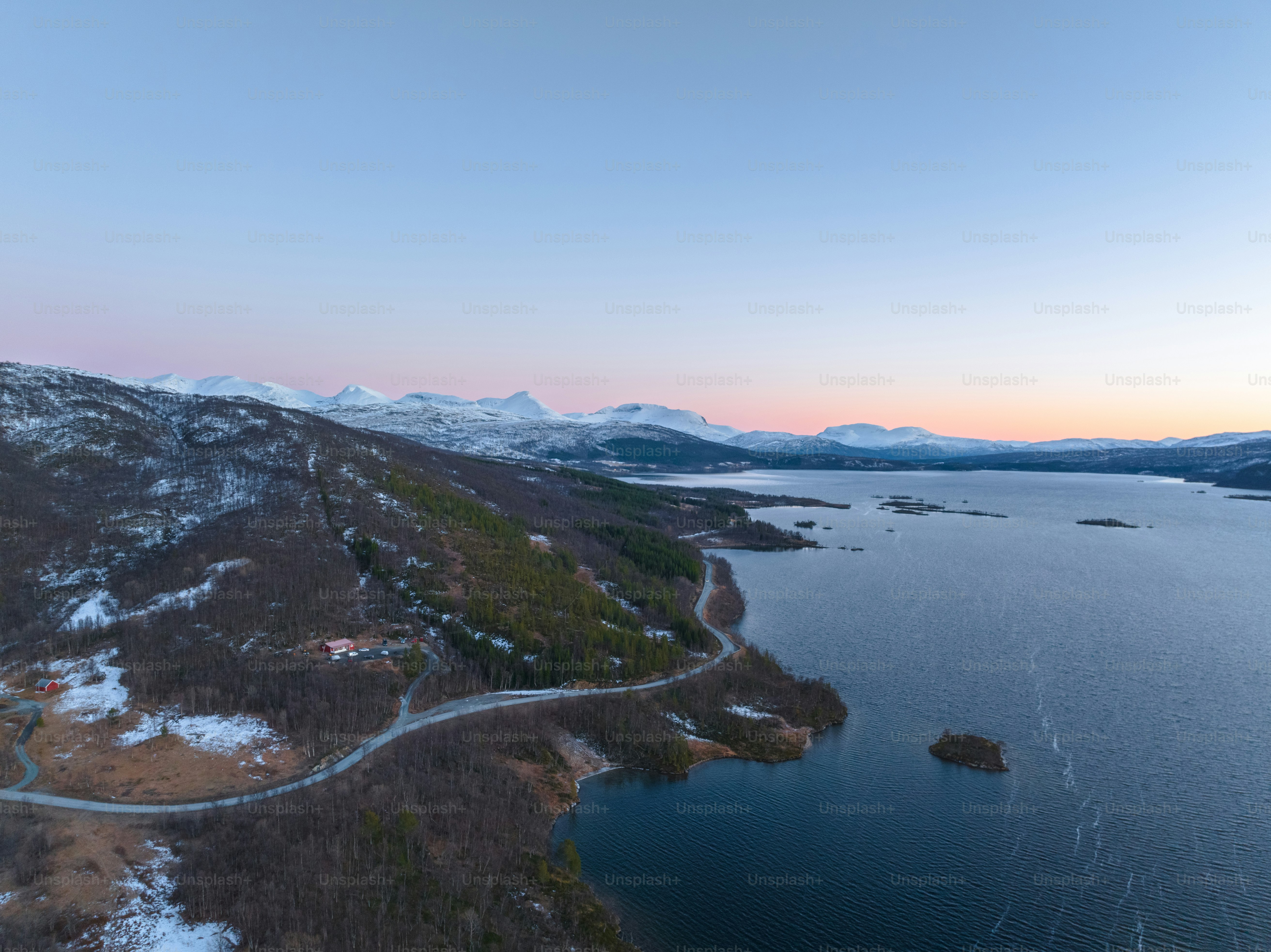 an aerial view of a lake surrounded by snow covered mountains