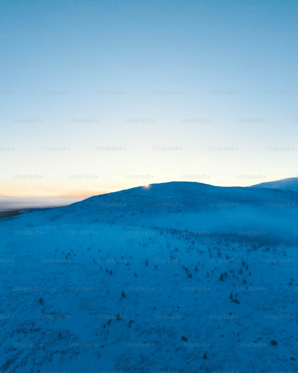 a hill covered in snow with a blue sky in the background
