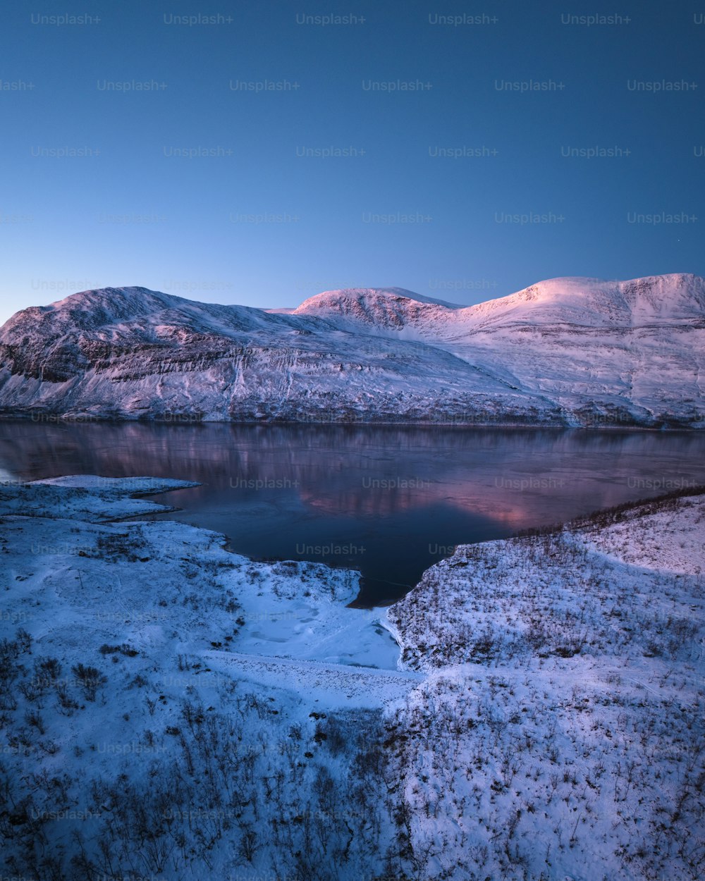 Un lago rodeado de montañas cubiertas de nieve bajo un cielo azul