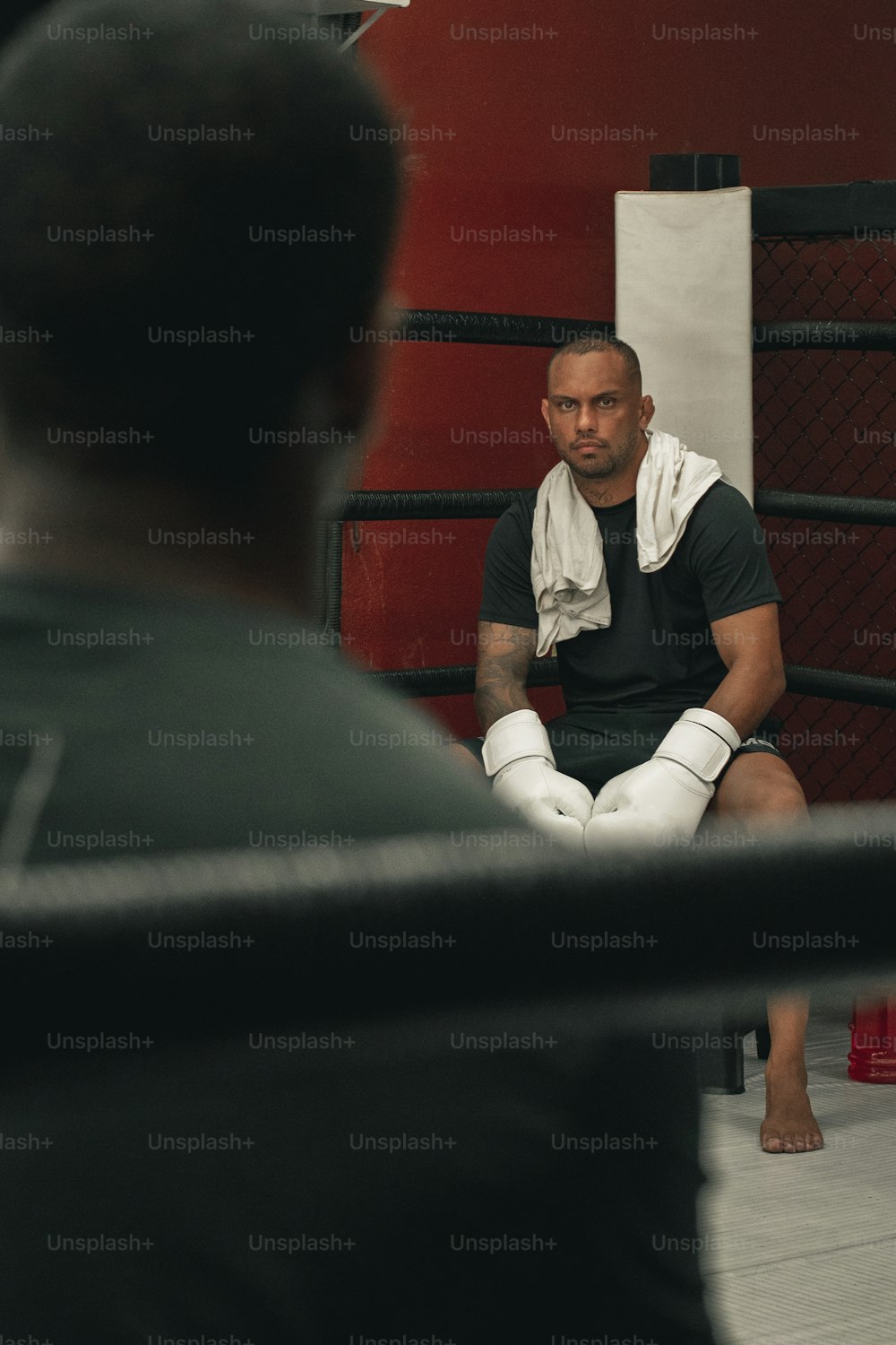 Un homme assis par terre sur un ring de boxe