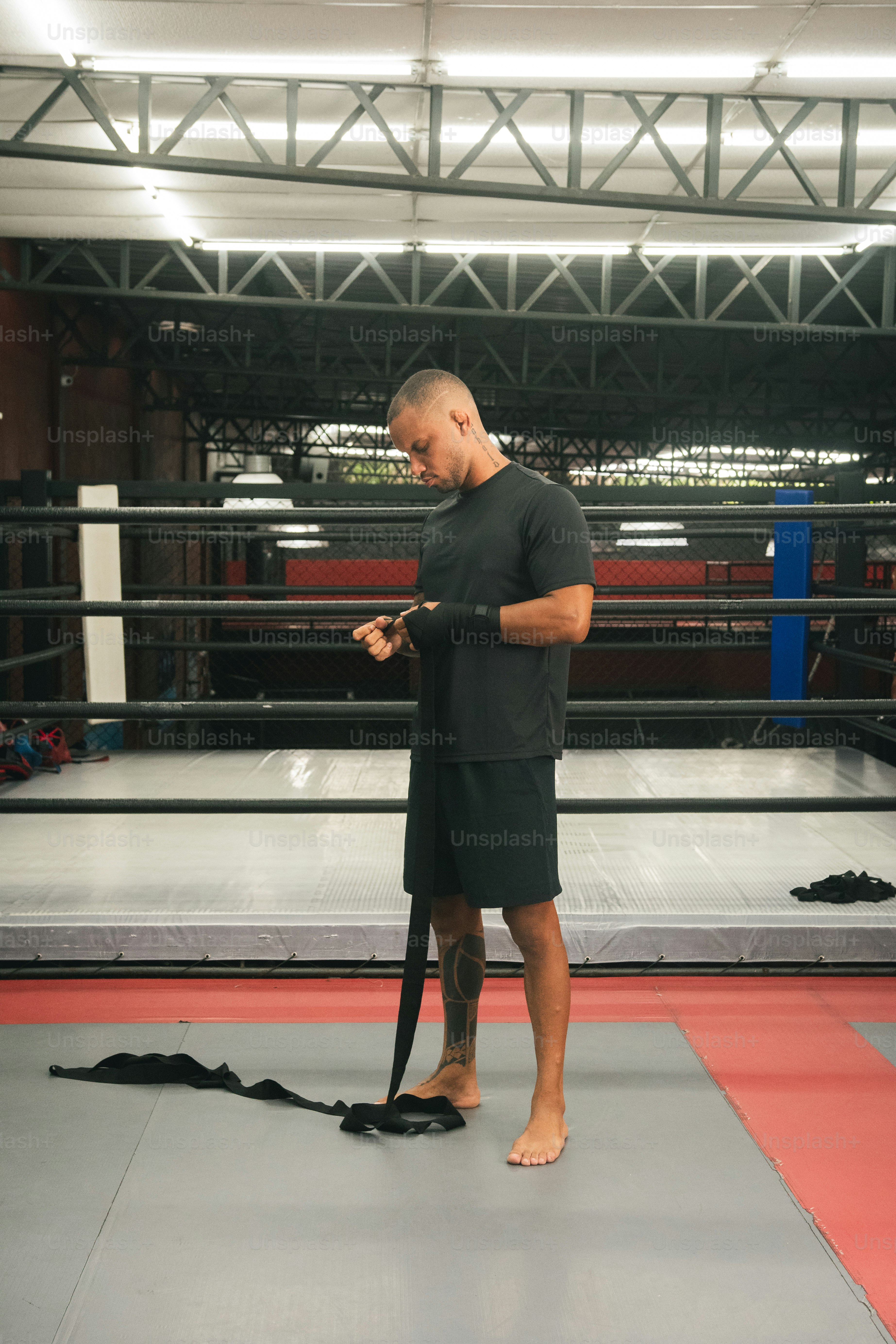 Un uomo in piedi su un ring di wrestling che guarda il suo cellulare