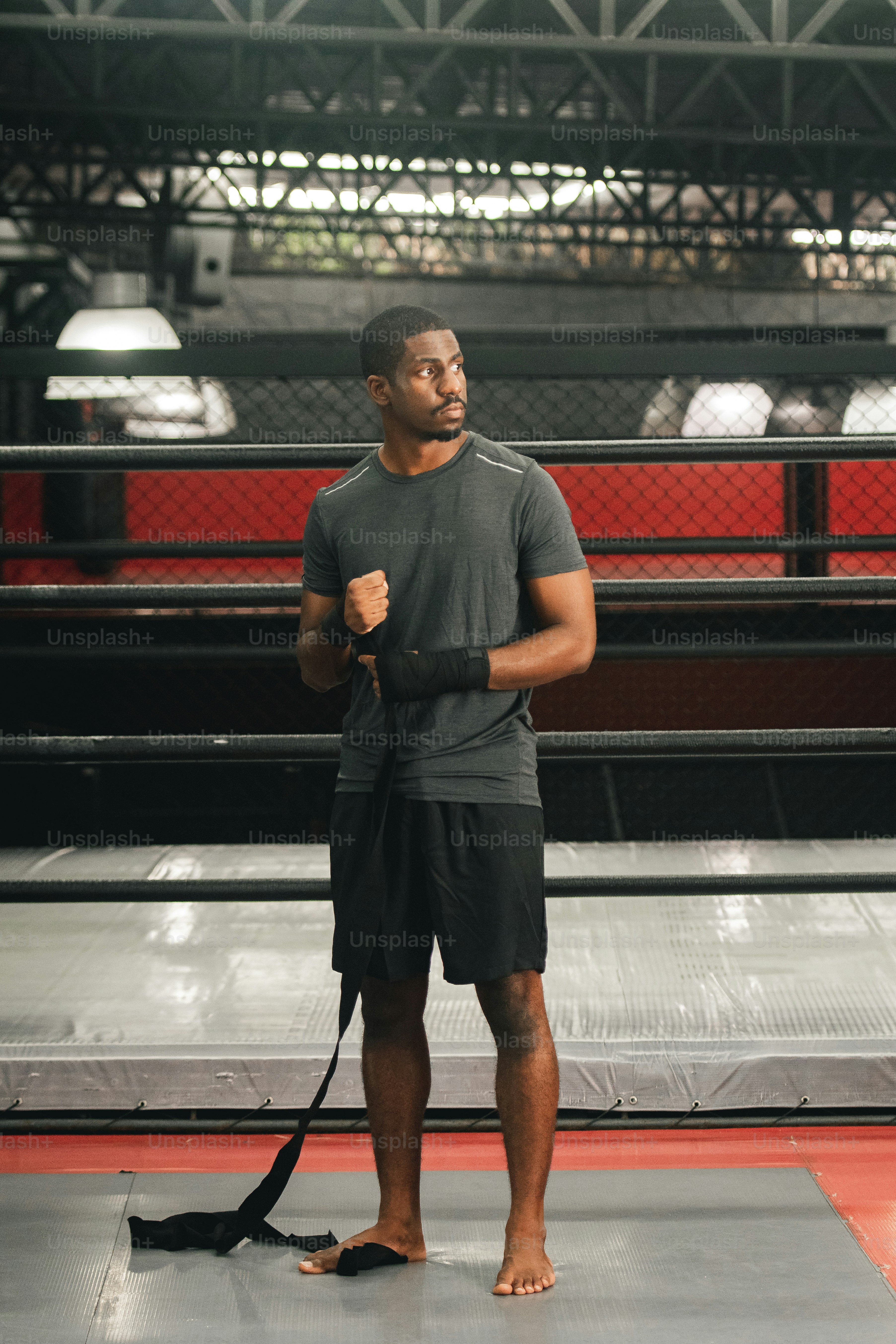 a man standing on a wrestling mat holding a black belt