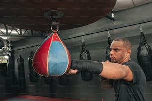 Un hombre en un gimnasio golpeando un saco de boxeo