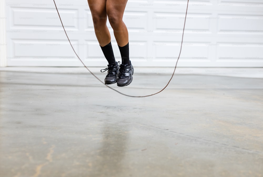 a woman in black shorts and black shoes jumping on a rope