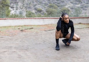 a woman squatting on the ground in a black outfit