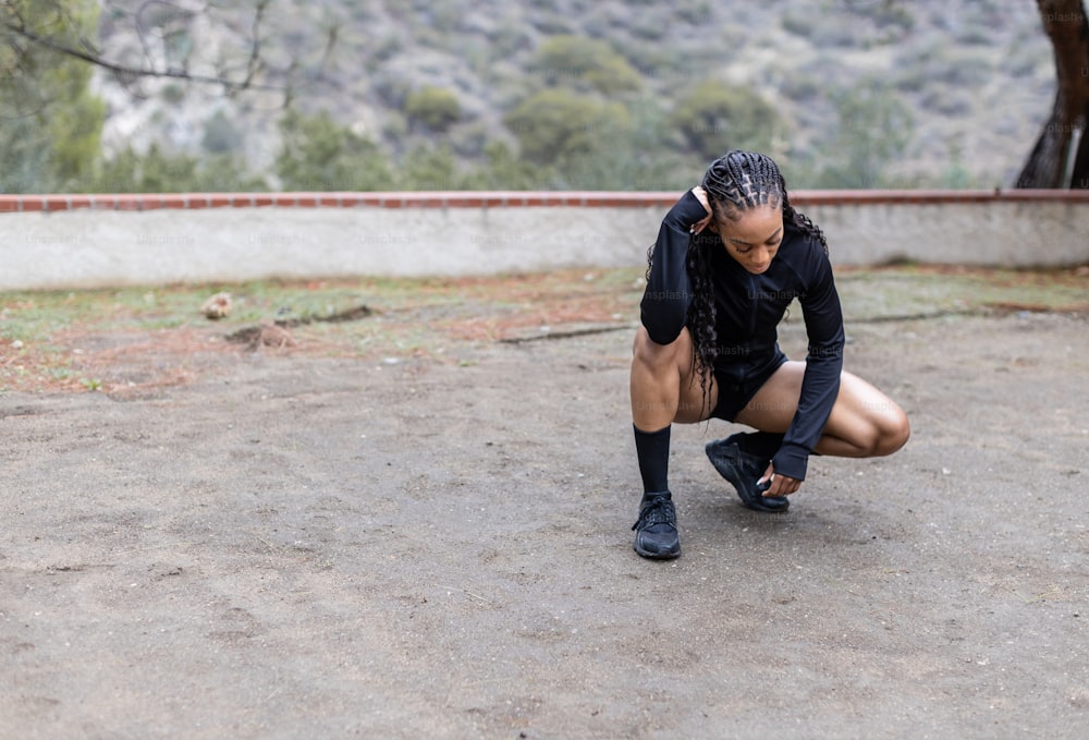 a woman squatting on the ground in a black shirt