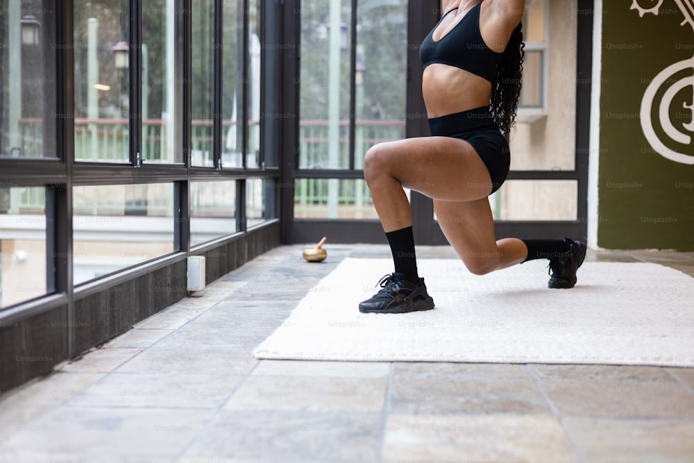 Une femme vêtue d’un haut de soutien-gorge de sport noir et d’un short noir fait un exercice accroupi