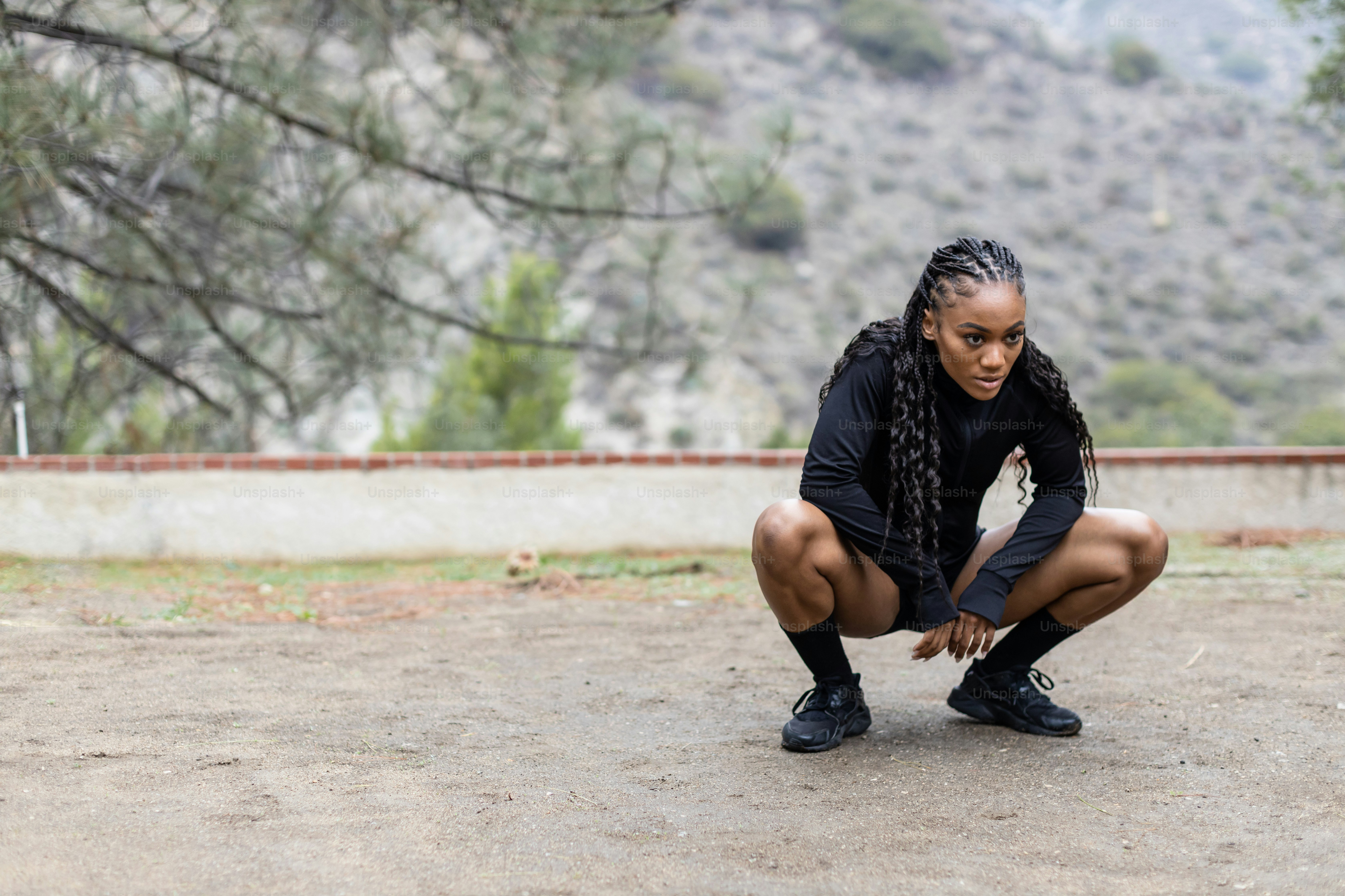 a woman squatting down in a dirt field