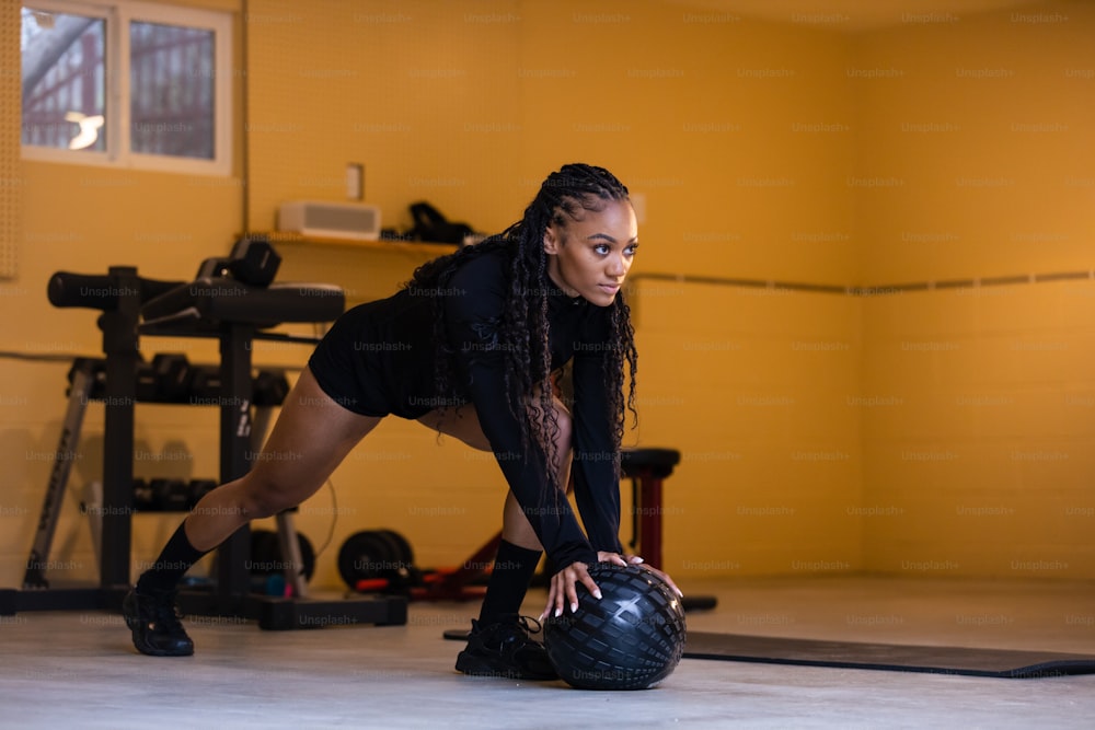 a woman in a gym squatting with a bowling ball