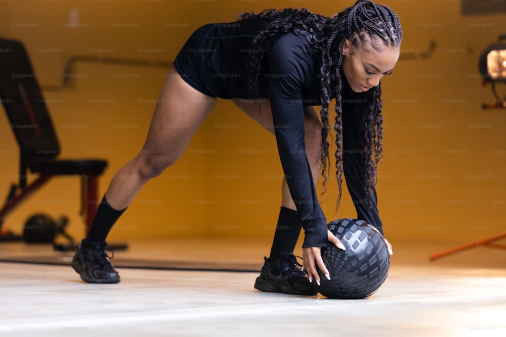 a woman bending over to pick up a bowling ball