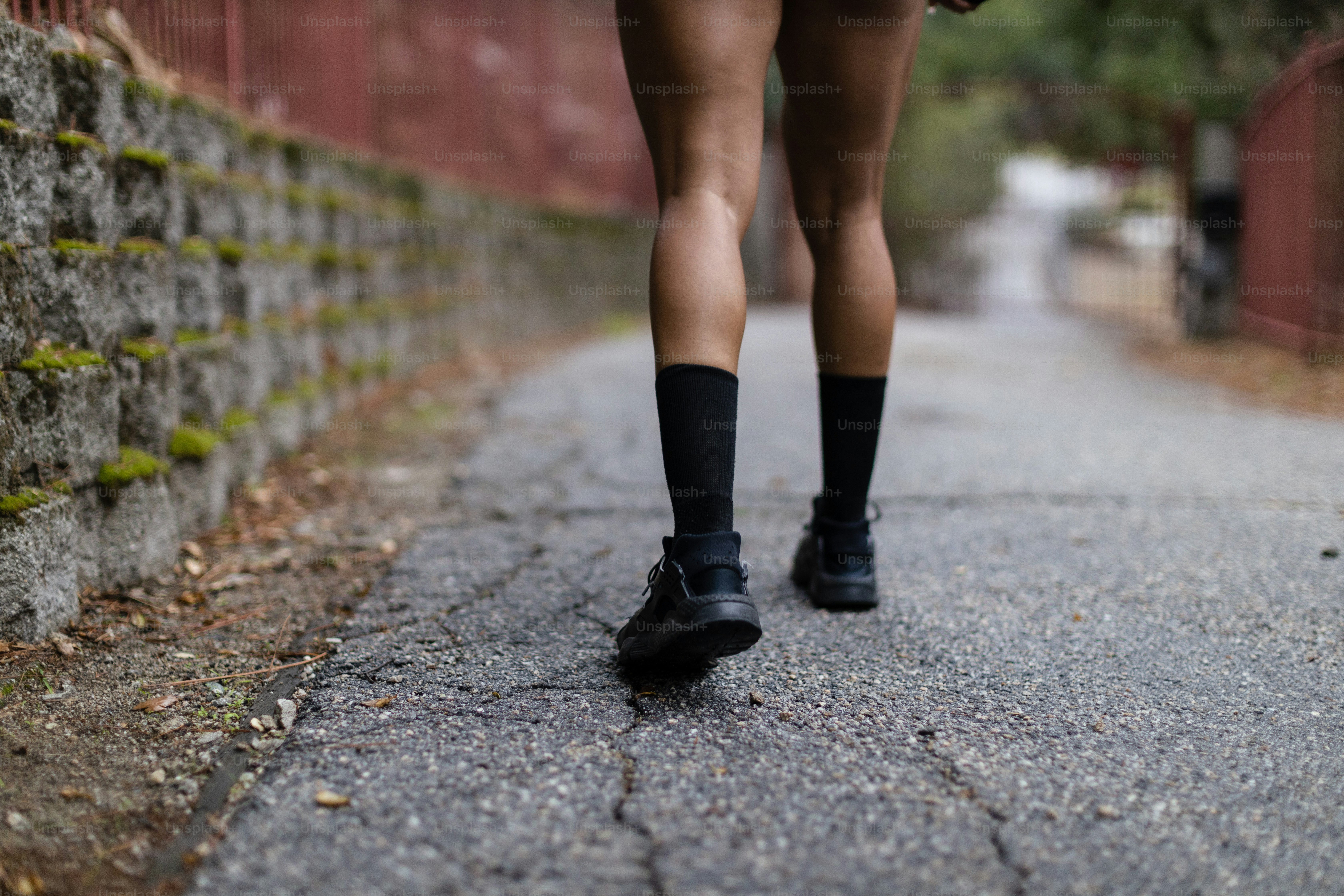 Une femme marchant dans une rue à côté d’un mur de briques