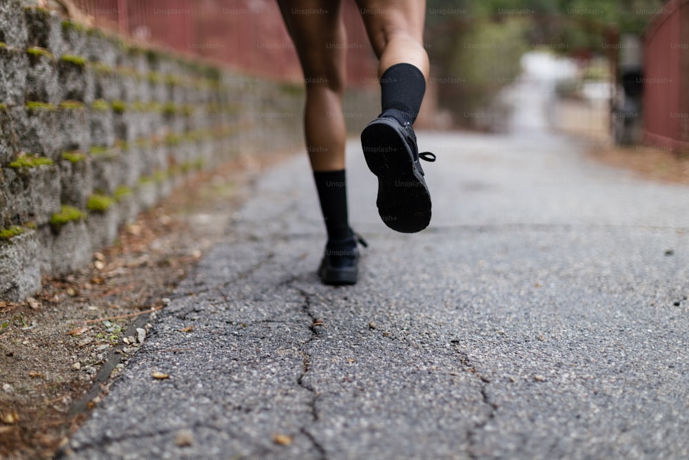 Eine Person, die mit schwarzen Schuhen eine Straße entlang läuft