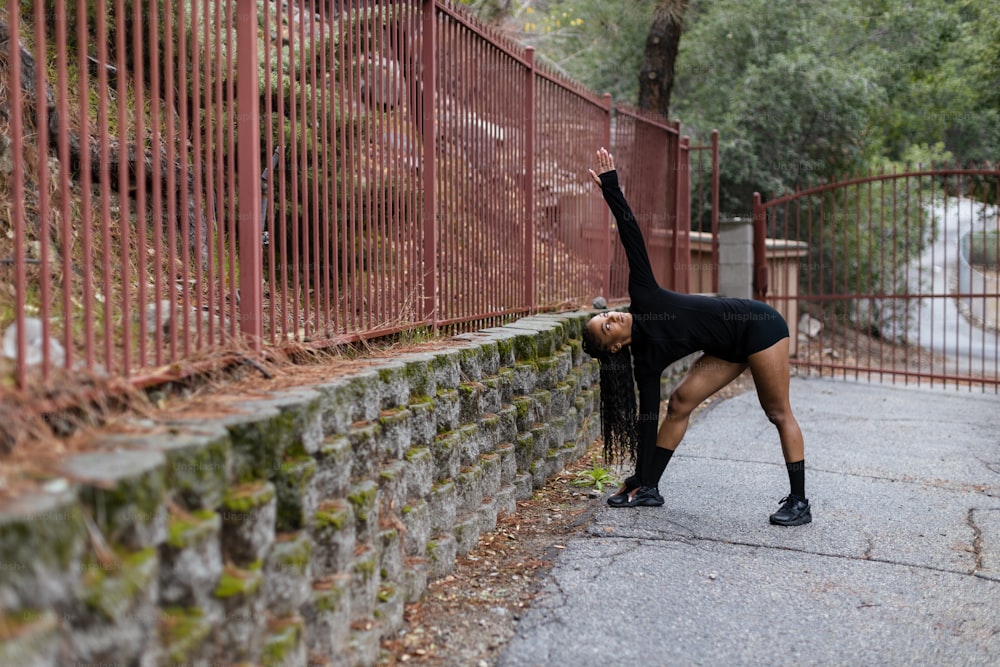 a woman is doing a handstand in front of a fence