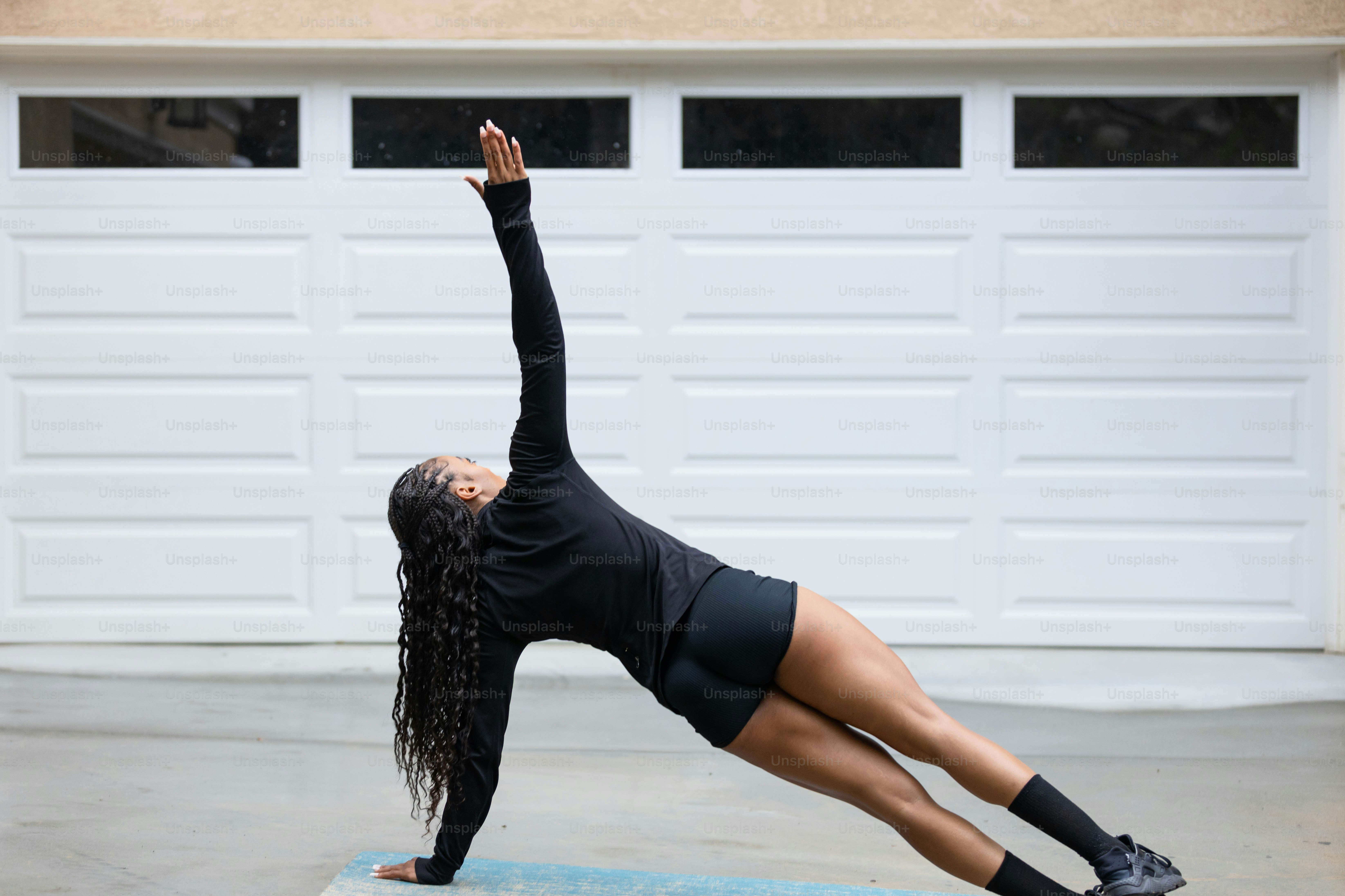 Una donna che fa una posa yoga davanti a un garage