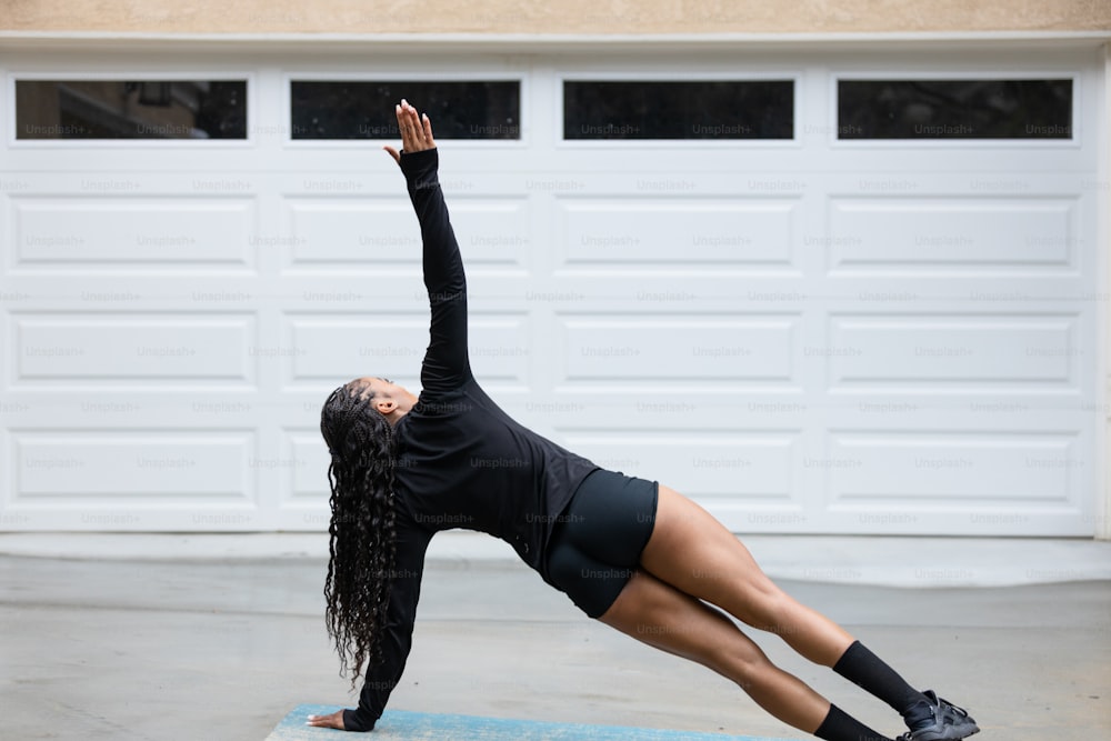 a woman doing a yoga pose in front of a garage