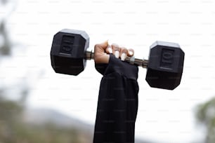 a person holding a pair of black dumbbells