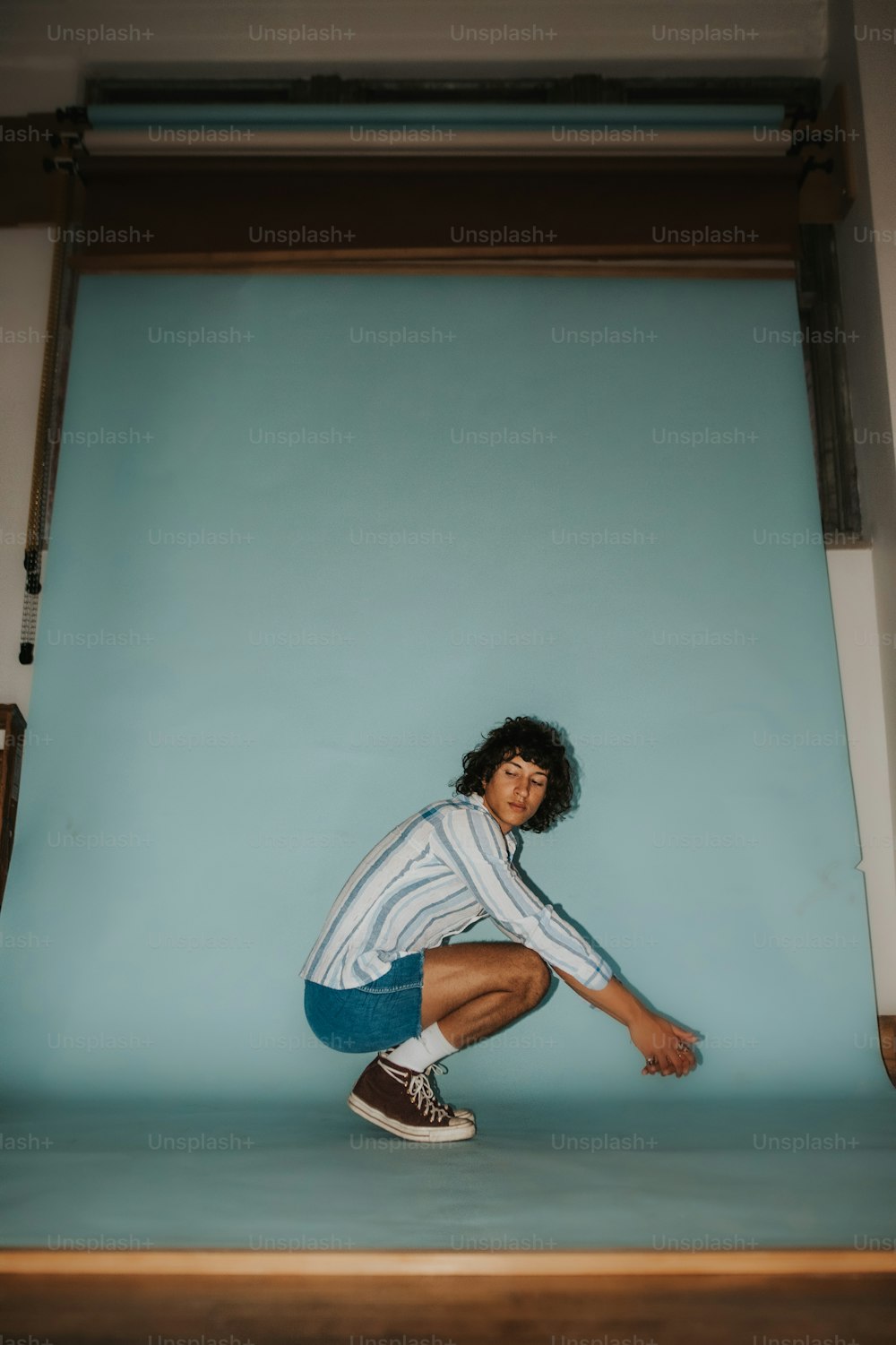 Un hombre en cuclillas en un escalón frente a una pared azul
