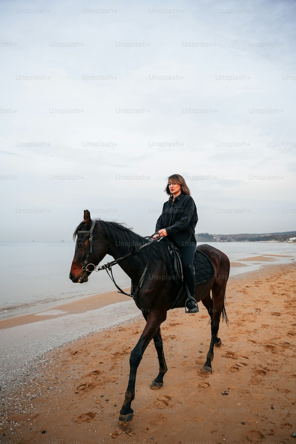 한 여자가 해변에서 말을 타고 있다