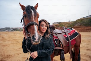 Una hermosa mujer de pie junto a un caballo marrón