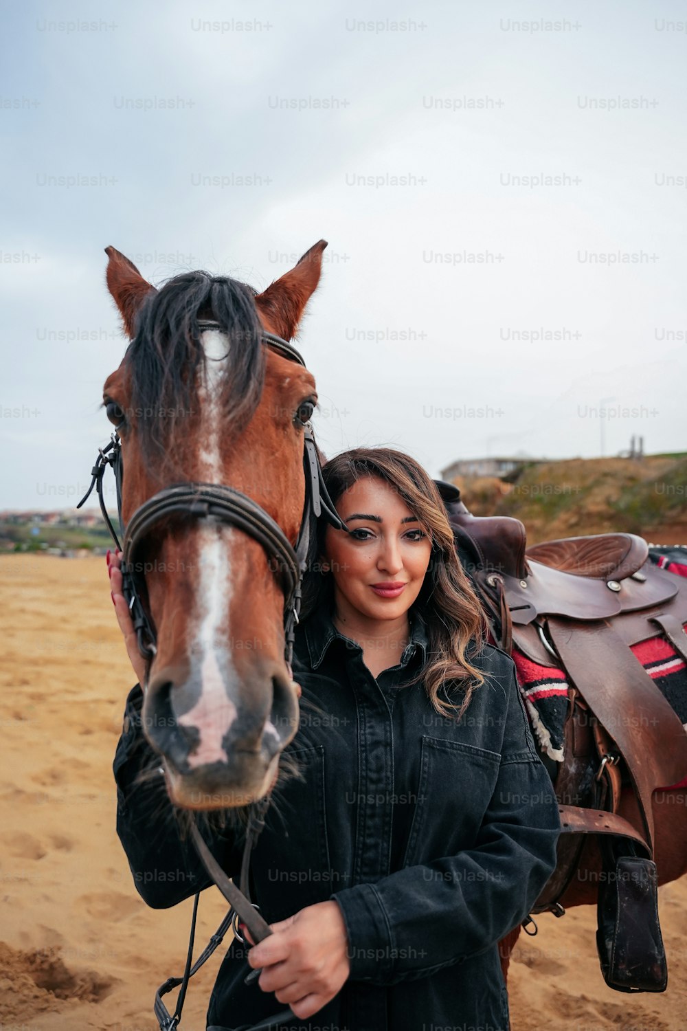 Una mujer de pie junto a un caballo marrón