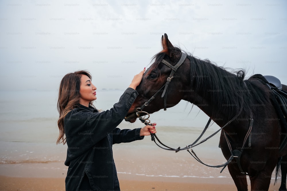 a woman is petting a horse on the beach