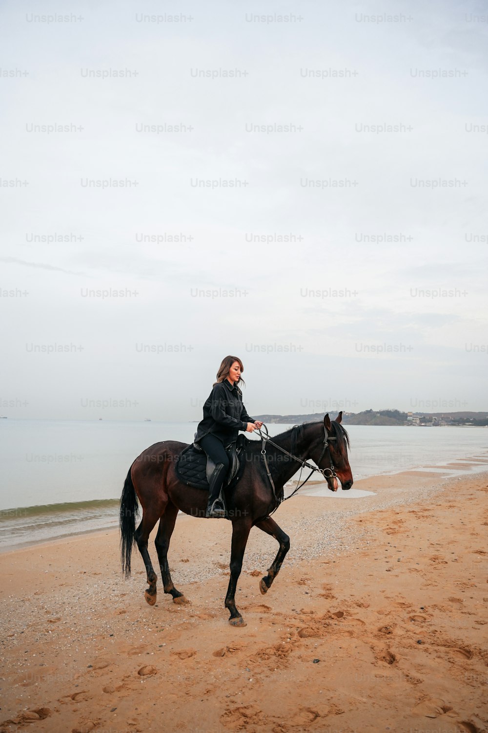여자가 해변에서 말을 타고 있다