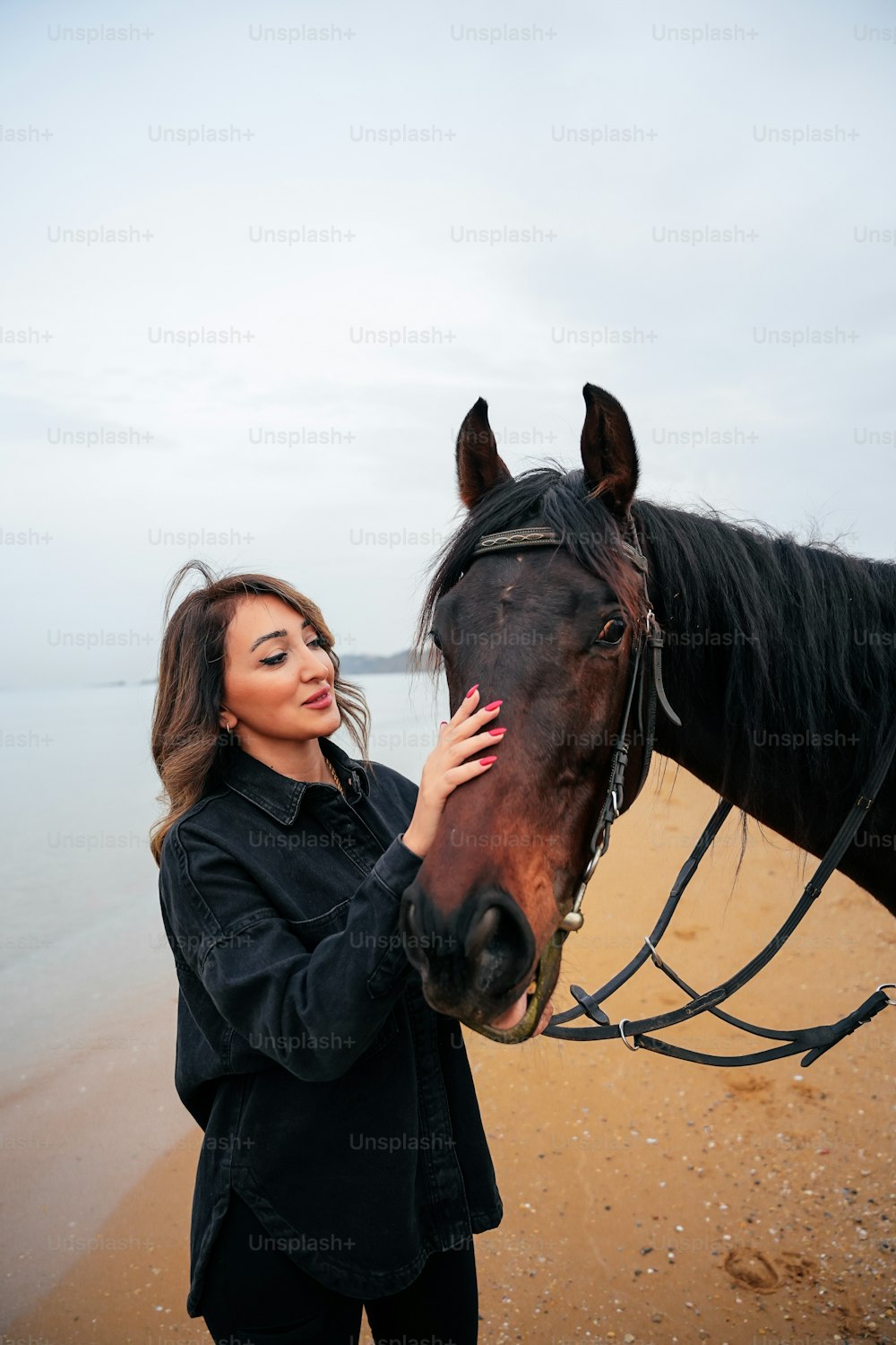 a woman is petting a horse on the beach