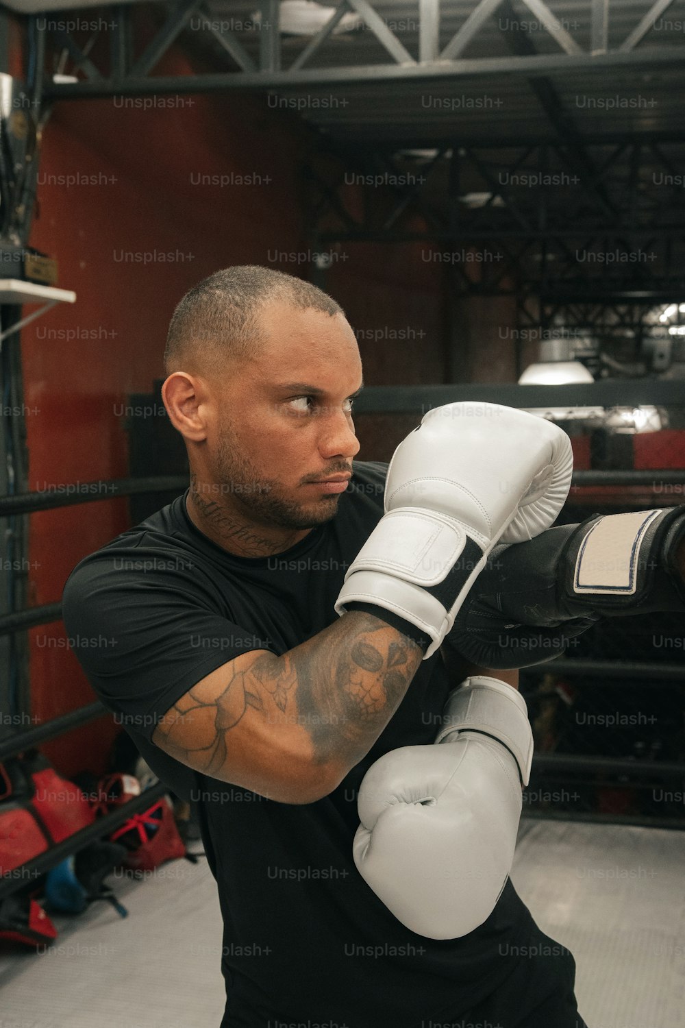 Un hombre con camisa negra y guantes de boxeo blancos