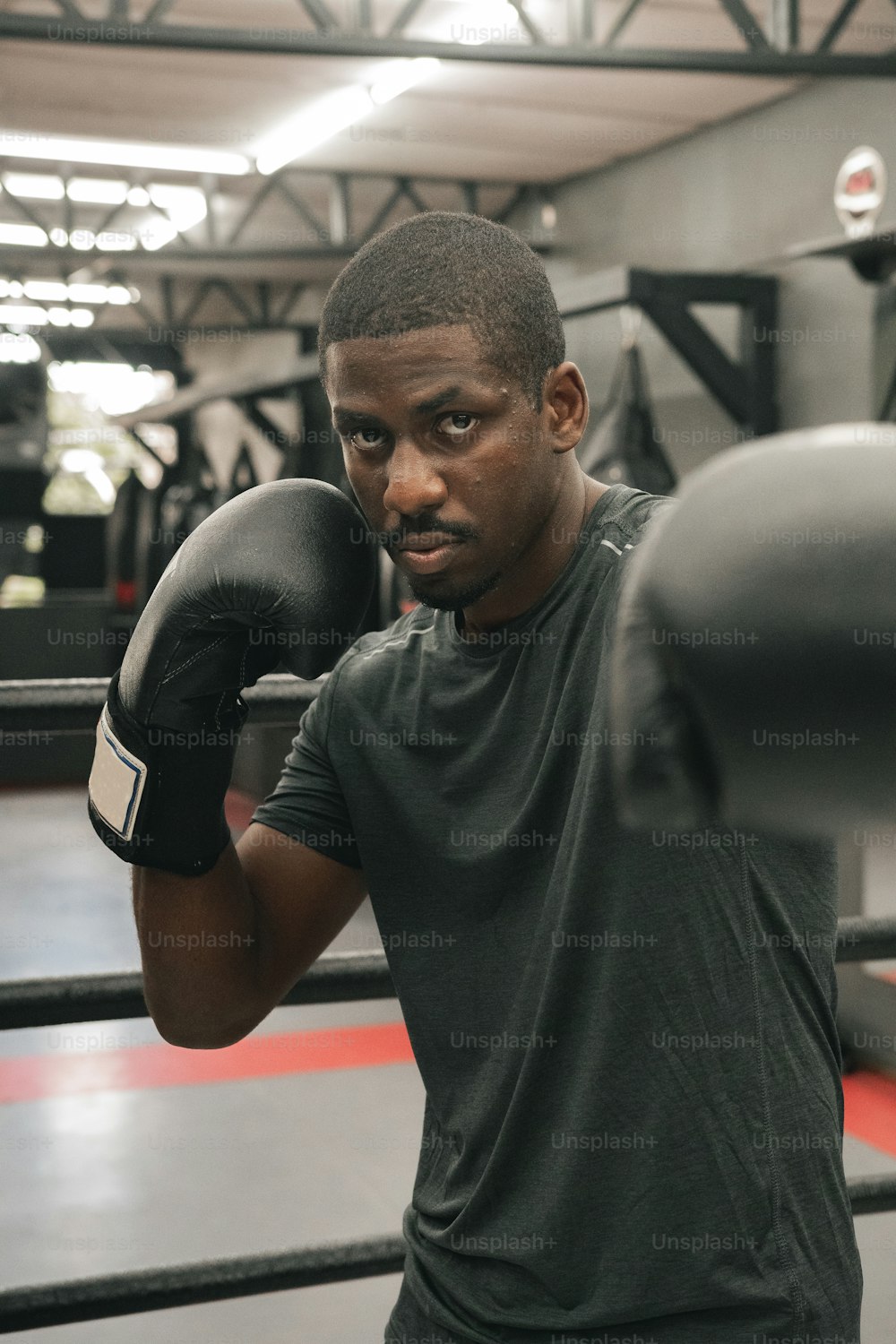 Un homme debout sur un ring de boxe tenant un gant de boxe noir