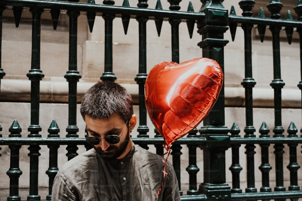 a man holding a red heart shaped balloon