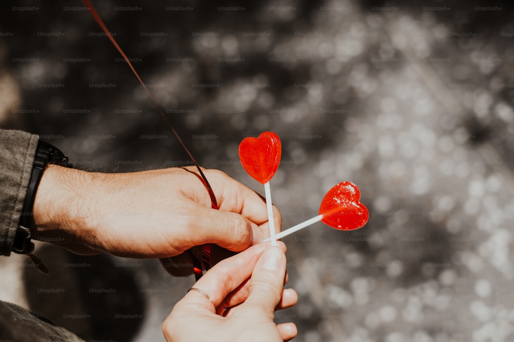 a person holding a lollipop with two hearts on it