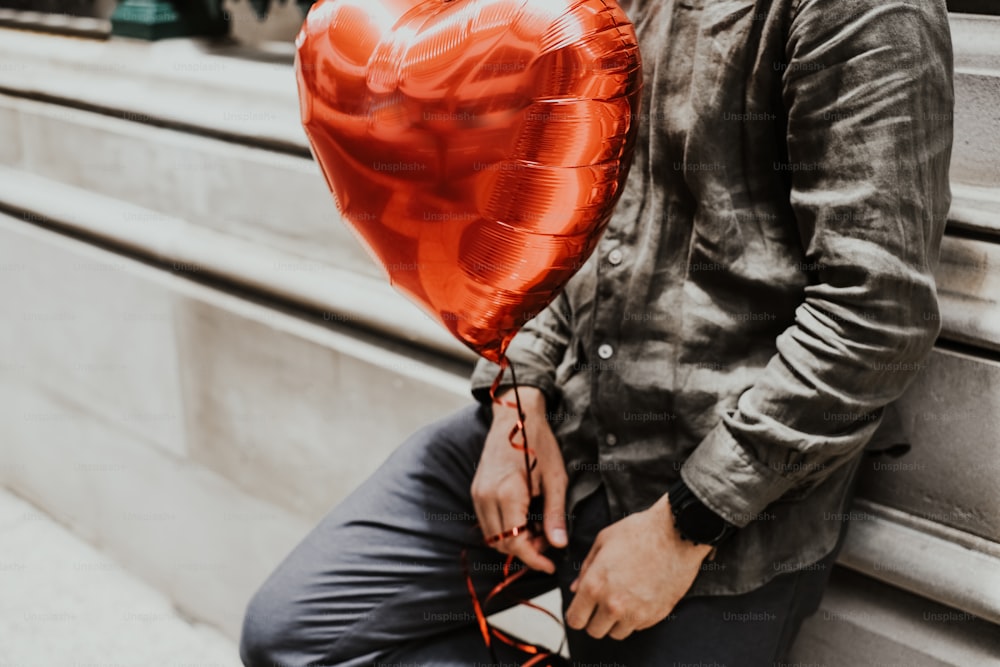 Un hombre sosteniendo un globo rojo en forma de corazón