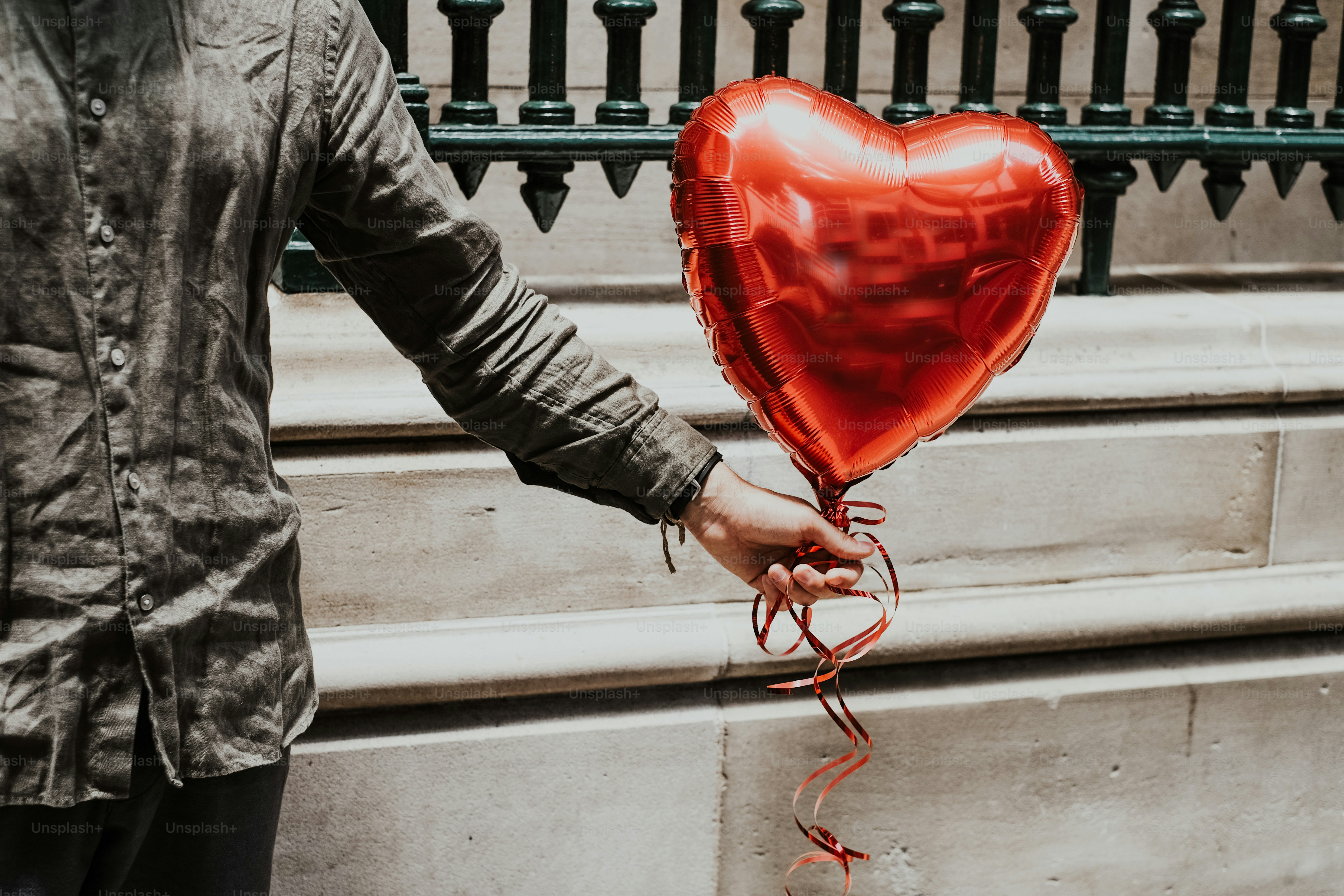 a person holding a red heart shaped balloon