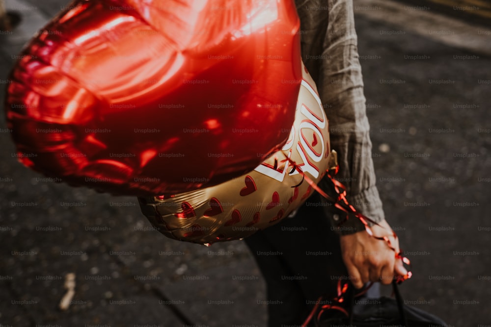 a person holding a red heart shaped balloon