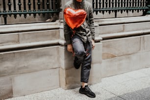 a person leaning against a wall with a heart shaped balloon