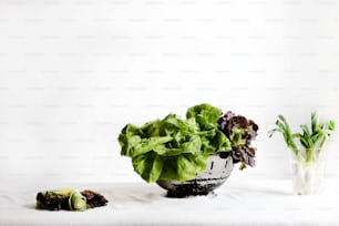 a bowl of lettuce next to a glass of water