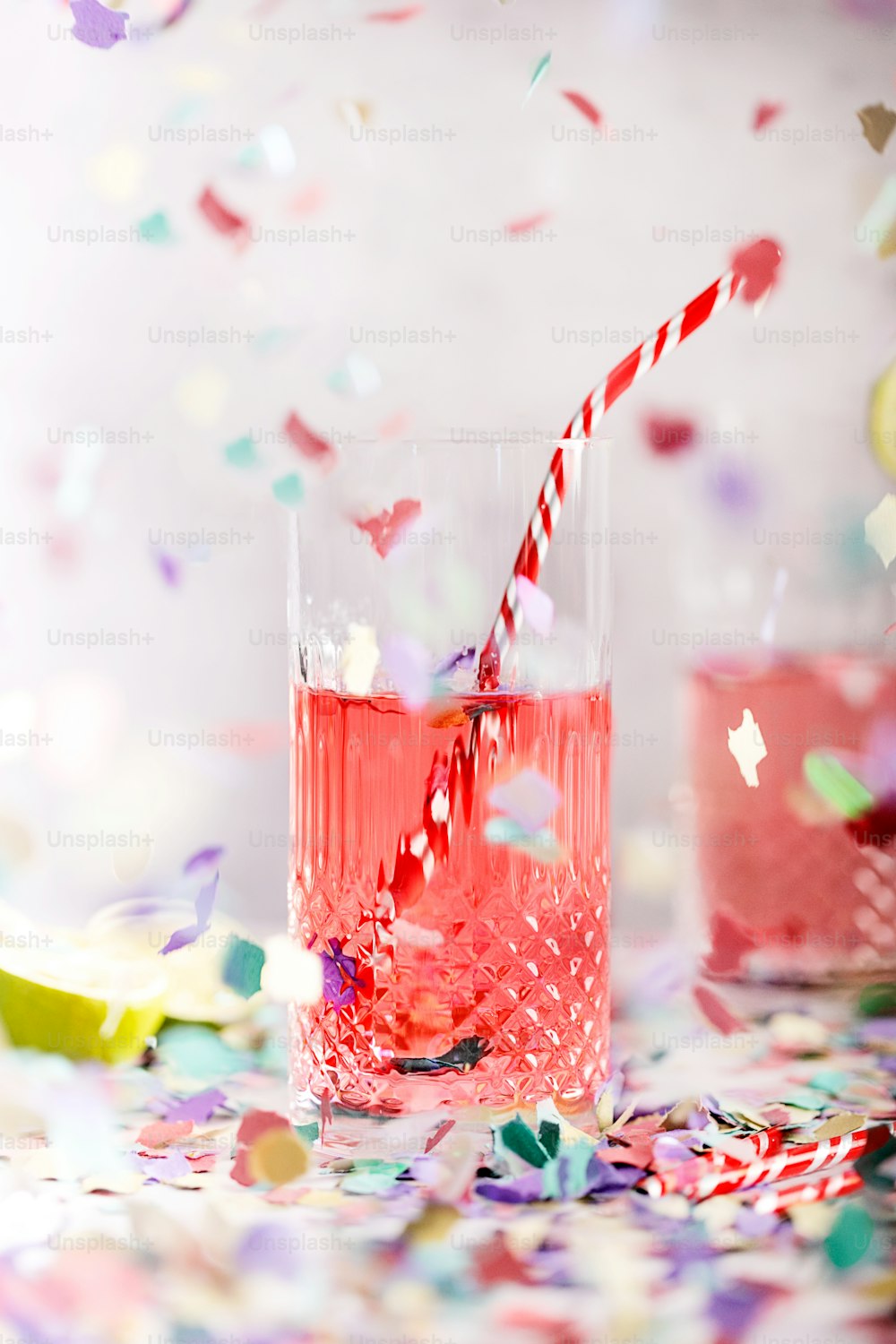 uma bebida rosa com um canudo cercado por confetes