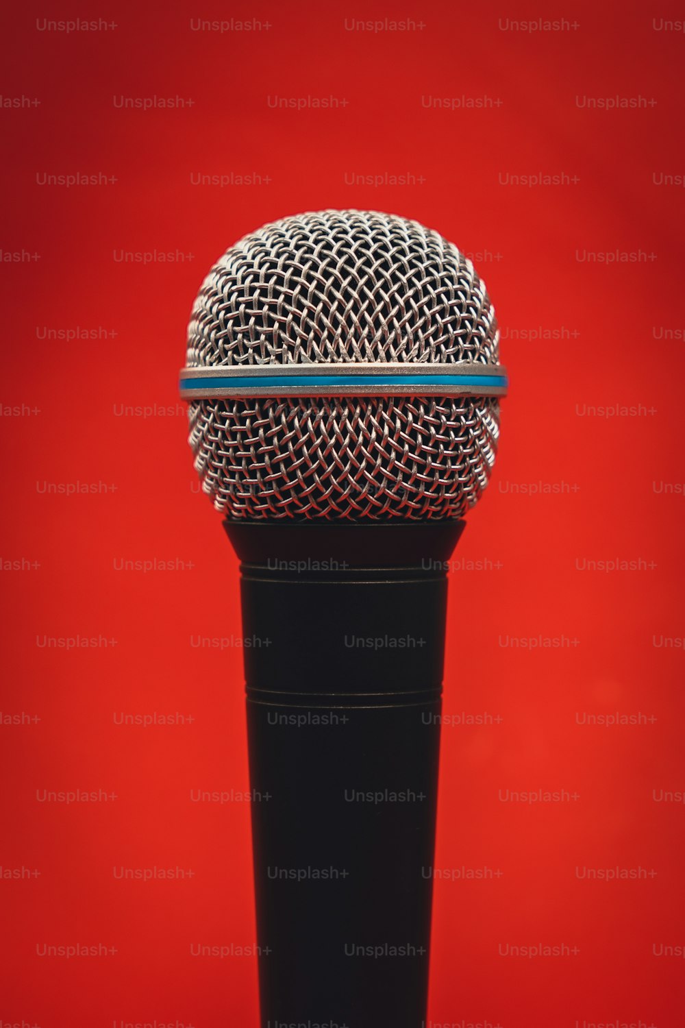 Un micrófono en un soporte sobre un fondo rojo