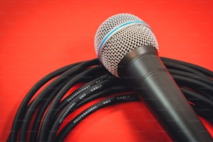 un microfono su sfondo rosso con un cavo nero