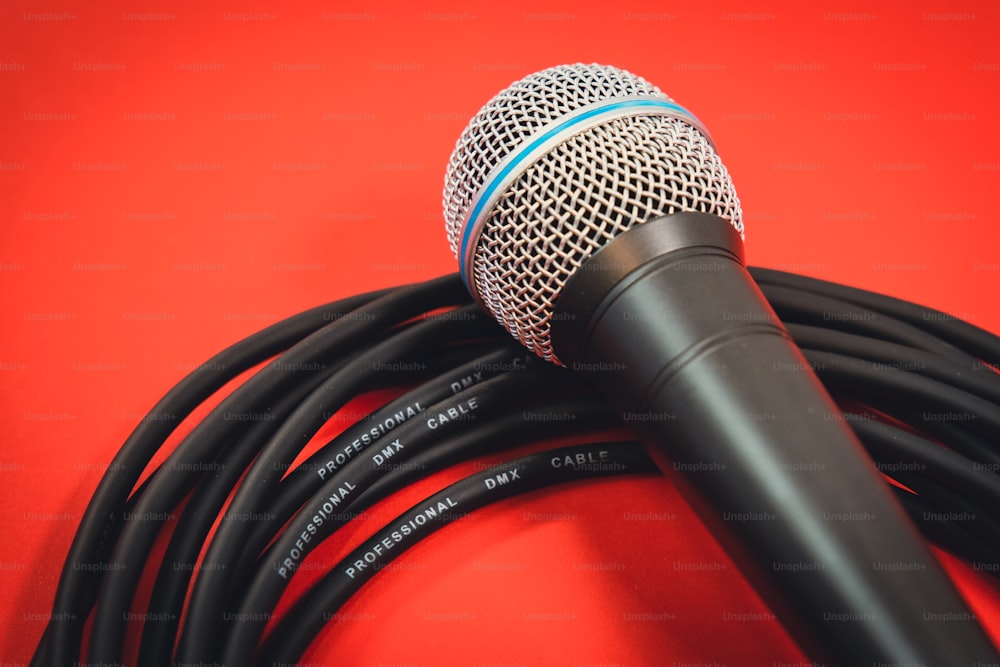 a microphone on a red background with a black cord