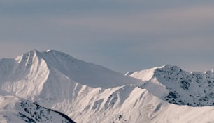 a large mountain covered in snow under a cloudy sky