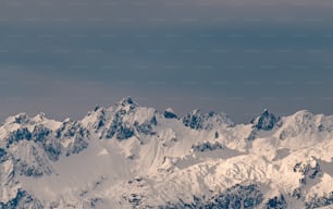 雪に覆われた山脈の上空を飛ぶ飛行機