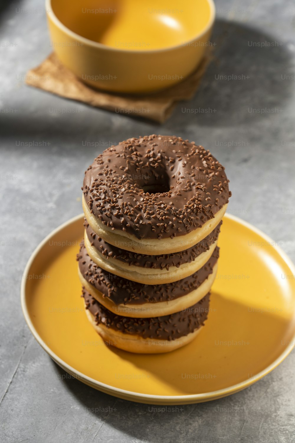 uma pilha de donuts de chocolate sentados em cima de um prato amarelo